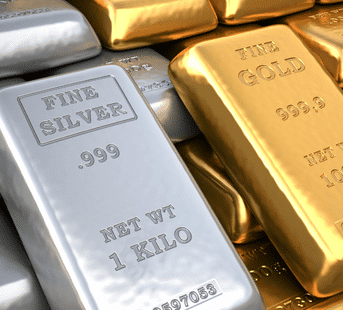 Stacks of shiny gold and silver bars, with some bars labeled “FINE SILVER .999 NET WT 1 KILO” and others labeled “FINE GOLD 999.9,” arranged closely together.