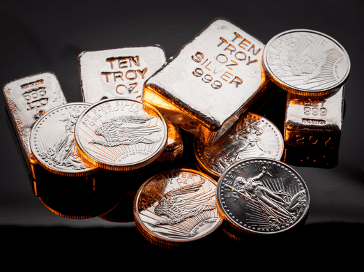 Stacks of silver bars and coins are arranged on a dark surface. The bars are labeled "TEN TROY OZ SILVER 999," and the coins have detailed designs, reflecting light with a shiny, metallic finish.