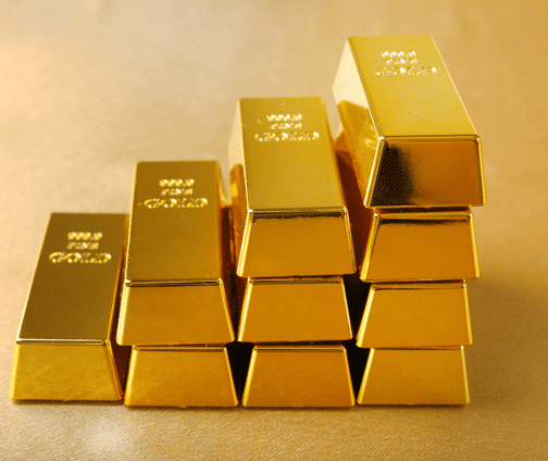 A stack of ten shiny gold bars is arranged on a golden surface, with four bars on the bottom row, three on the second, two on the third, and one on top, all reflecting light.