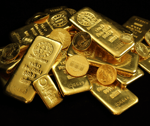 A pile of gold bars and gold coins stacked together on a black surface, with visible engravings indicating their weight, purity, and origin.